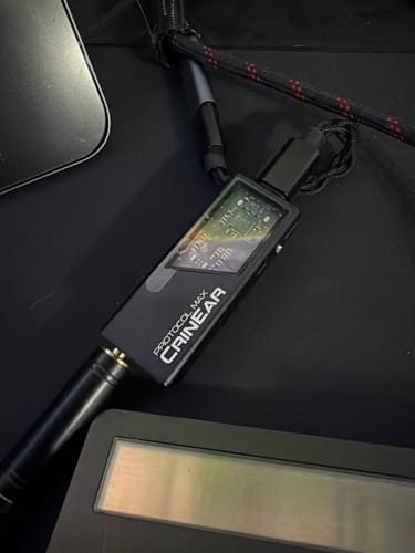 A customer's black CrinEar Protocol Max DAC/Amp on a desk with a headphone plug inserted.