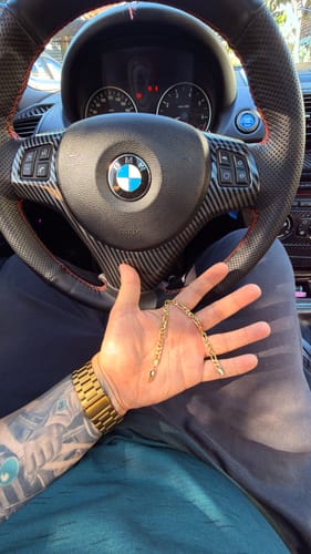 Cliente sosteniendo la Pulsera Fígaro Oro en su mano dentro de un coche.