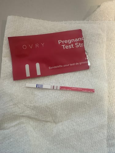Reviewer's Ovry Pregnancy Test Strip showing a strong positive result, with the test line darker than the control line.