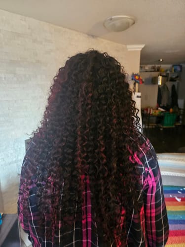 Customer's back view, showing the long, voluminous BOBBI BOSS DEEP WAVE weave with dark and reddish curls.