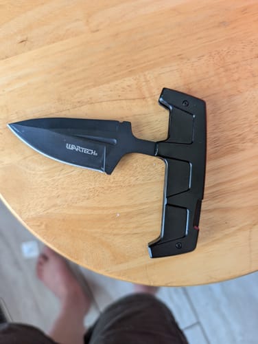 Customer's Black Transformer Fixed Push Dagger shown in its unfolded form on a wooden table.