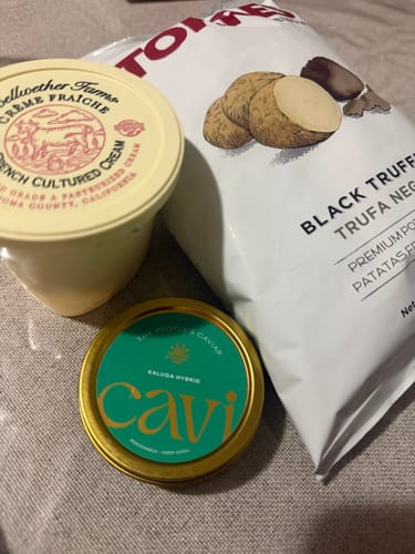 Customer's tin of Kaluga Hybrid Caviar shown with truffle potato chips and crème fraîche.