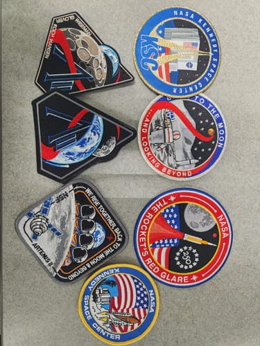Reviewer's Artemis II - Collectors Patch displayed with a collection of six other assorted space-themed patches.