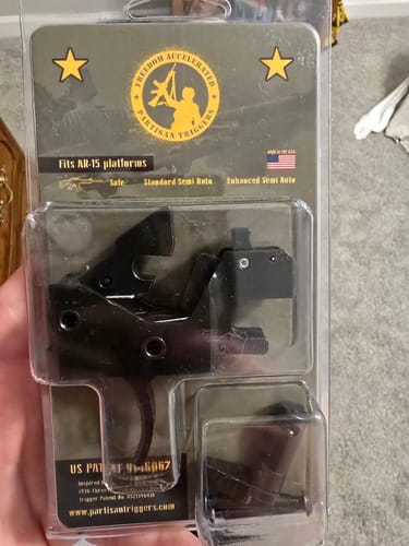 Customer holding the Partisan Disruptor FRT AR-15 drop-in cassette trigger in its packaging.