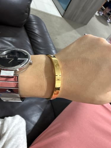 Reviewer wearing the gold Carrie Stainless Steel Bangle on their wrist, next to a watch.