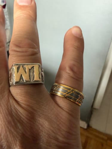 Customer's hand wearing the Bravado ring, showing its brushed silver finish and gold-accented grooves.