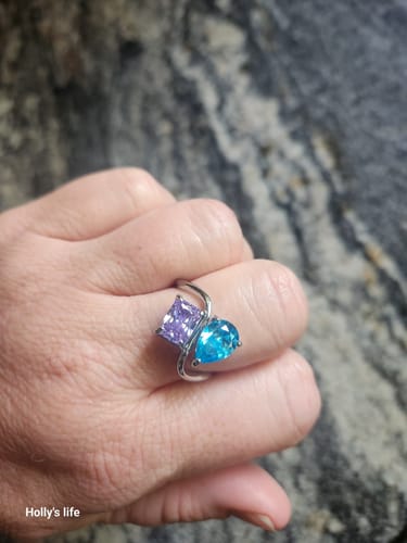 Reviewer's hand wearing the Navae Birthstone Ring with a purple radiant-cut and a blue pear-cut stone.