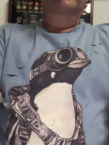 Customer wearing the light blue Dream Beyond Limitations t-shirt with a detailed penguin pilot graphic.