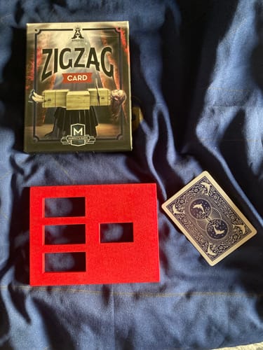 Customer's Zig Zag Card magic trick components, including the box, a red frame prop, and a playing card.