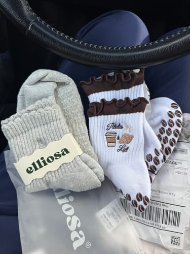 Customer's gray Dual-Direction Grip Basics socks next to another pair of socks on a person's lap.