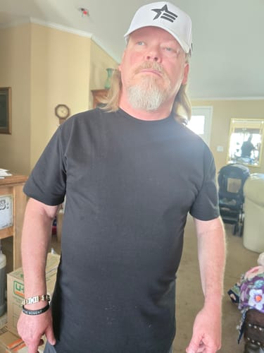Reviewer standing indoors wearing the black Signature Line Drop Cut Shirt.