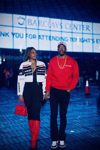 Customer wearing the black Vortex Stacked Denim with a red sweatshirt while standing outdoors at night.