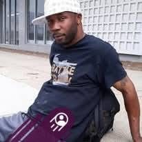 A reviewer for Nitric Oxide Plus pictured sitting on a sidewalk.