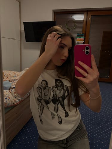 Customer taking a mirror selfie in a bedroom wearing the after party classic tee.