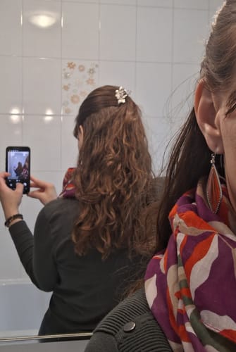 Rezensentin zeigt ihr definiertes, gewelltes Haar in einer Spiegelaufnahme nach der Anwendung der CURL AWAKENING™ BOX.