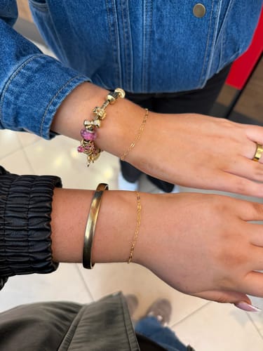 Two reviewers show their delicate, gold Sparked by FinerRings bracelets on their wrists side-by-side.