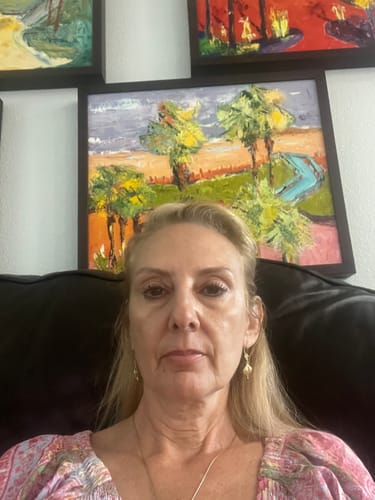 Reviewer's selfie taken indoors in front of some paintings.