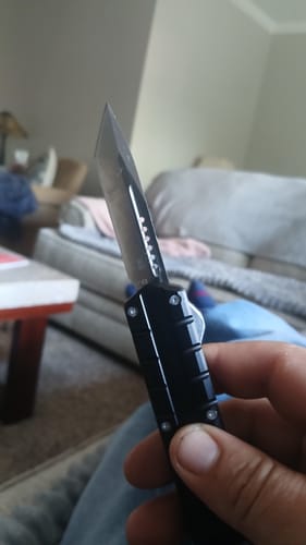 Customer holding the small black Triton D/A OTF knife with the tanto-style blade extended.