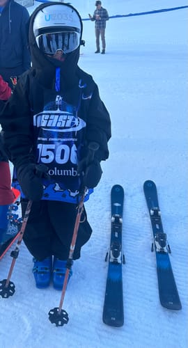 Customer wearing the black balloon snow pants while standing on a snowy ski slope.