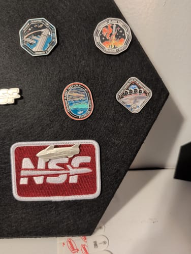 Customer's Artemis II Collectors Pin displayed on a black felt board with other space-themed pins.