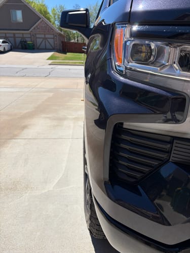 Close-up of a customer's dark gray truck, showing the front tire extending past the fender with 1.5" wheel spacers installed.