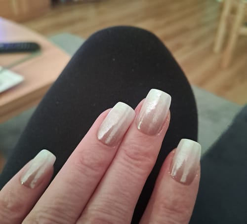 Hand einer Kundin mit den Babyboomer Nude UV Gel-Folien, veredelt mit einem glänzenden Chrompuder.