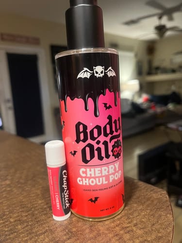 Customer's Cherry Ghoul Pop Body Oil placed next to a cherry ChapStick to illustrate its similar scent.