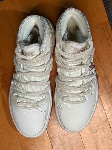 Customer's pair of white Joker 2 "MIRO" High shoes shown top-down on a wooden surface.
