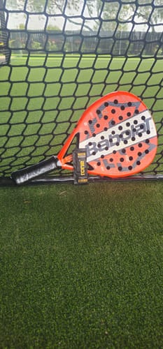 Customer's SuperCharged Honey packet leaning against a padel racket on a green court.