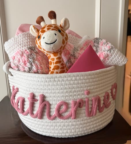 Reviewer's white rope basket personalized with the name Katherine, filled with a stuffed giraffe and a crocheted afghan.