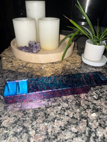 Reviewer's open, colorful metal pill case resting on a granite countertop.