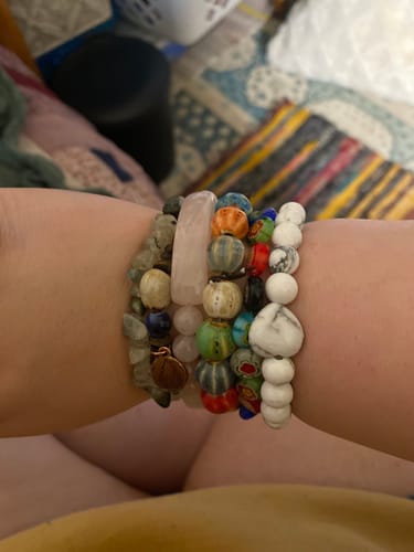 Customer's wrist showing a stack of bracelets including a rose quartz one from their AuraBloom Subscription Box.