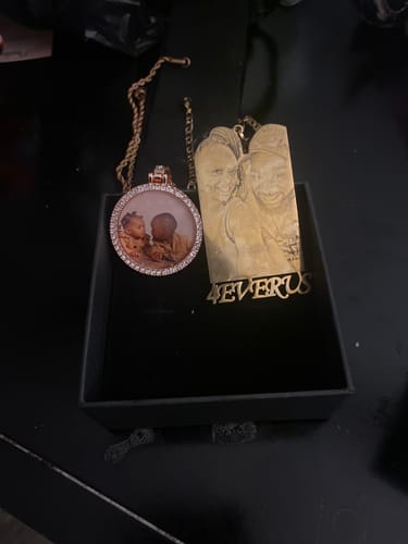 Customer's round studded photo necklace and rectangular gold-plated pendant in an open black jewelry box.