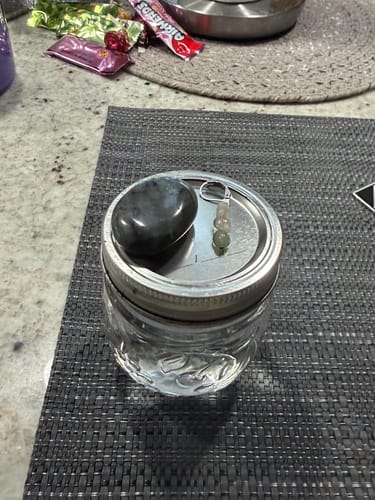 Reviewer's dark, polished crystal sitting on a glass jar of water on a placemat.