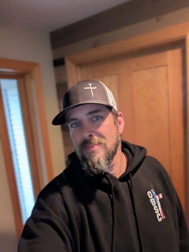 Customer wearing the dark gray and white 3 Nail Cross Prayer Print Hat indoors.