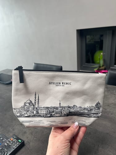 Recensent houdt de lichte Luxe Toilettas met een gedetailleerde Istanbul-print vast.