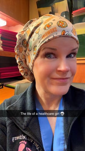 Reviewer in a medical office wearing the patterned 'Showgirl' DuoStyle Scrub Hat, styled in a slouchy fit.
