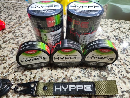 Customer's green Tactical Keychain with keys, shown on a counter with several tins of nicotine pouches.