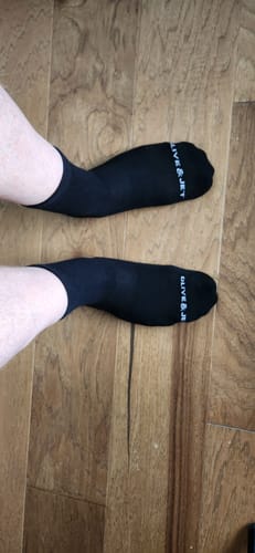 Reviewer's feet wearing the black Quarter Socks, viewed from above on a wooden floor.