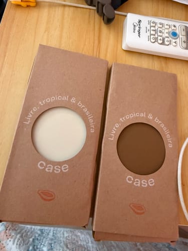 Avaliadora exibe duas embalagens da Case, uma na cor creme e outra marrom, sobre uma mesa de madeira.
