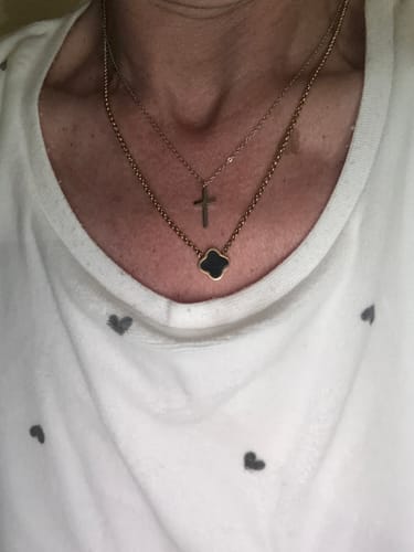 Close-up of a customer wearing the black Celine Clover Necklace, layered with another thin cross necklace.