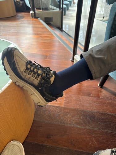 A reviewer's leg wearing a dark Performance Eucalyptus Compression Sock inside a sturdy hiking shoe.