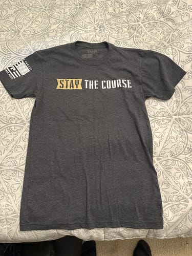 Reviewer's dark grey T.V.P. Elite Membership t-shirt with 'STAY THE COURSE' printed in gold and white on the front.
