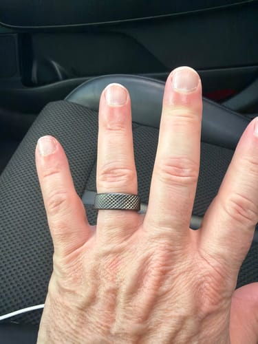 Customer's hand wearing the wide Barbell Set ring, highlighting its dark, knurled texture.