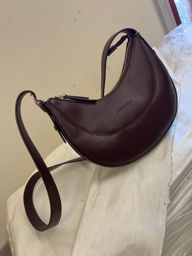 Customer's photo of the chocolate Lane Crossbody Bag, showing its sleek half-moon shape and strap.