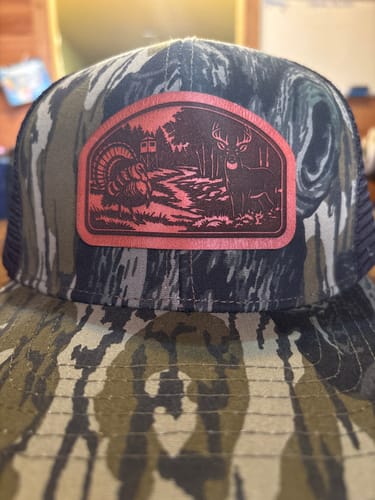 Customer's custom Mossy Oak trucker hat with a leather patch showing a deer and turkey scene.