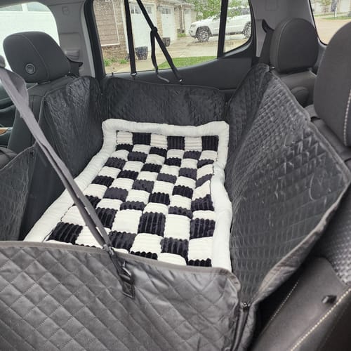 Customer's black quilted car seat hammock cover installed in the back seat of a car, with a checkered blanket inside.