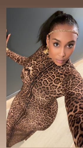 Reviewer posing in the fitted, long-sleeved Naked Leopard Maxi Dress.