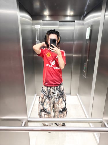 Reviewer taking a mirror selfie in an elevator to show the fit of their Graffiti Mud Wash Baggy Jeans.