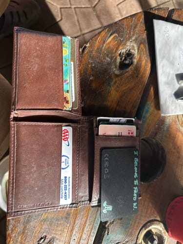 Reviewer's black SPOTMINDERS Tracking Card, personalized with writing, shown inside an open brown leather wallet.